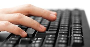 Hand typing at keyboard. Photo by Tyler Olson via Shutterstock.