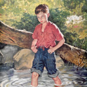 A boy wading through a stream.
