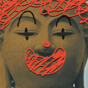 Statue of Buddha with clown makeup scribbled over its face.