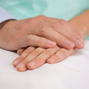 A doctor's hand resting on his patient's.