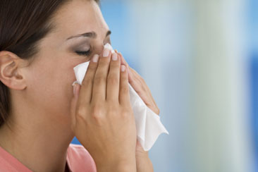 A woman sneezing into a piece of tissue.