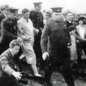Golfer Bobby Jones is led by police through a mob.