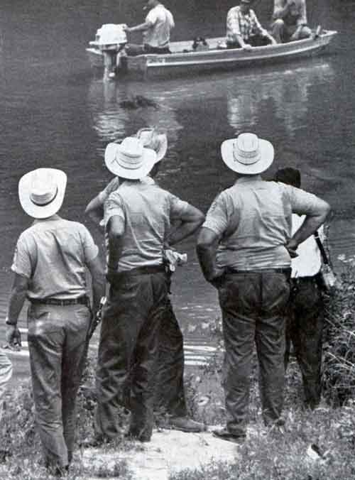 “Men in skiff prepare to drag the Pearl River for bodies of three missing civil-rights workers while search party on the bank stops to watch.” <br /> Photo credit Lynn Pelham. © SEPS 1964