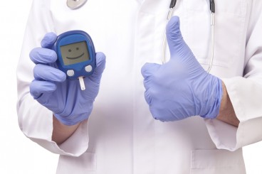 doctor holding glucose monitor with a smiley face on it