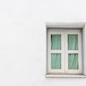 A small, white-framed window on a blank white wall.