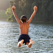 Boy jumping into a lake.