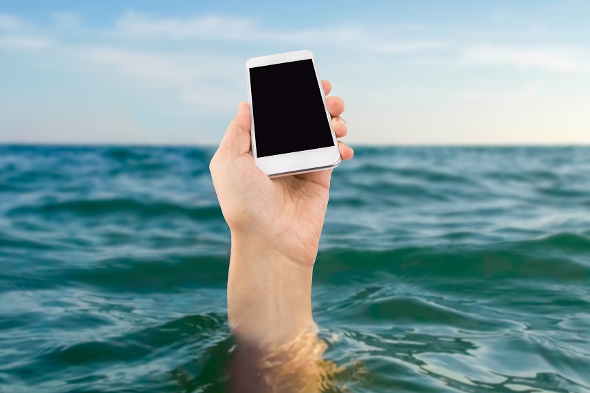 The hand of a submerged swimmer sticks their iPhone out of the water.