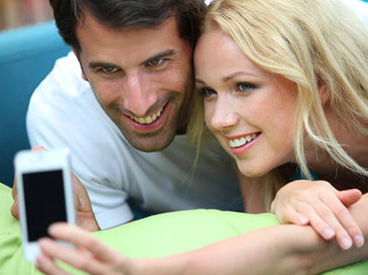 Couple taking pictures of themselves with mobile phone. Courtesy of Shutterstock.