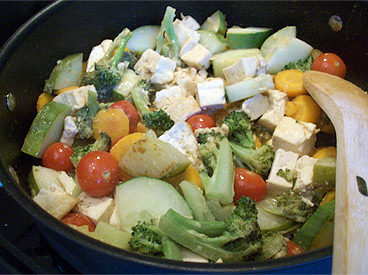 cucumber, peppers, cherry tomatoes, tofu, and broccoli cooking in pot