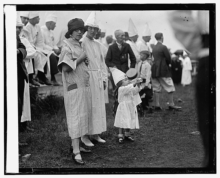 Women and their daughters at a Ku Klux Klan meeting. One of the children can be seen in a Klan robe.